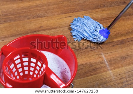 red bucket with water and mopping of parquet floors