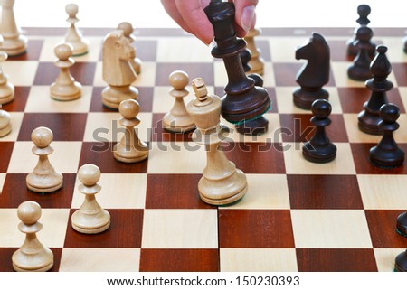 hand with black king beats white king on chessboard in chess game