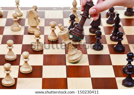 hand with black king pushes white king on chessboard in chess game