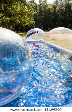 girl in water ball and many balls in open swimming pool