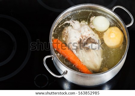 boiling of chicken broth in steel pan on glass ceramic cooker