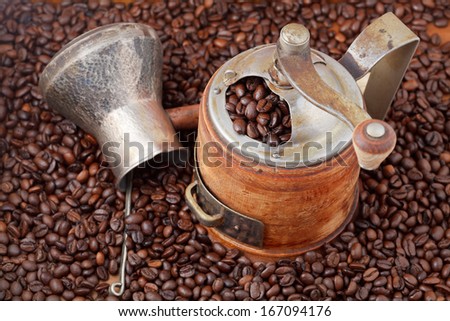 top view of retro manual coffee mill and copper pot on many roasted coffee beans