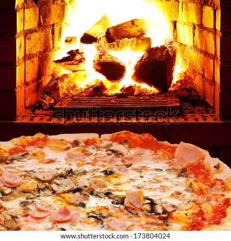 italian pizza with ham and mushrooms and open fire in wood burning oven