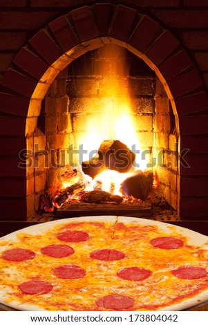 italian pizza with sausage and open fire in wood burning oven