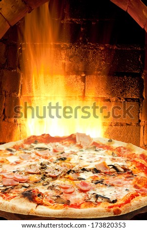 Italian Pizza With Ham And Mushrooms And Fire Flames In Wood Burning Oven