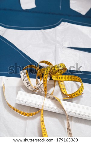 tailor measure tools and paper model of dress on blue fabric for dress cutting