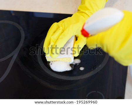 washing vitroceramic stove by sponge and detergent from spray bottle