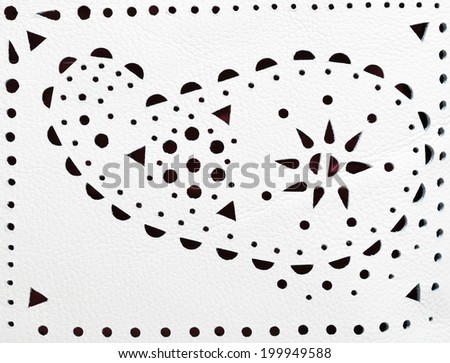 perforated paisley ornament on white leather close up