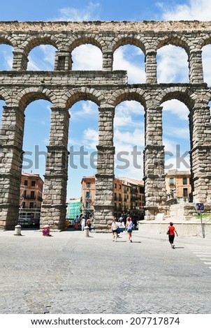 SEGOVIA, SPAIN - JULY 10, 2011: tourist near Aqueduct of Segovia on Plaza del Azoguejo. It consists of about 25000 granite blocks, has lenght about 818m, and height 29m.