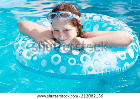 girl on inflatable circle in blue open-air pool in sunny day