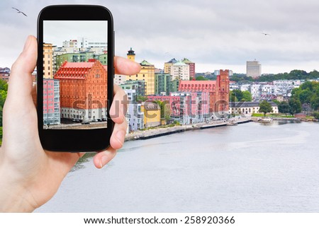travel concept - tourist taking photo of waterfront in Stockholm, Sweden on mobile gadget