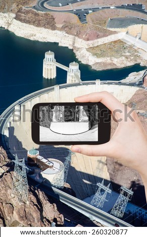 travel concept - tourist taking photo of above view of of Hoover Dam on mobile gadget, USA