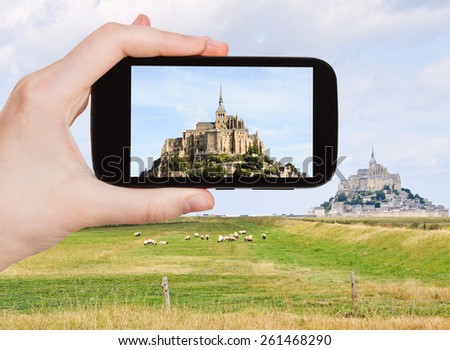 travel concept - tourist take photo of mont saint-michel abbey, Normandy, France on mobile gadget