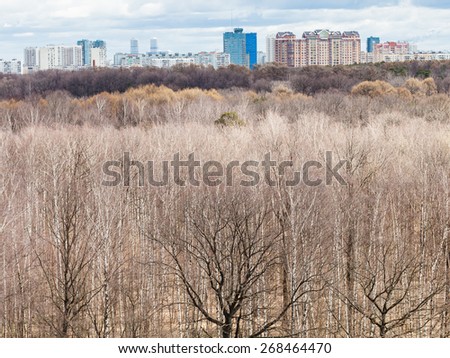 above view of bare trees in spring forest and urban houses