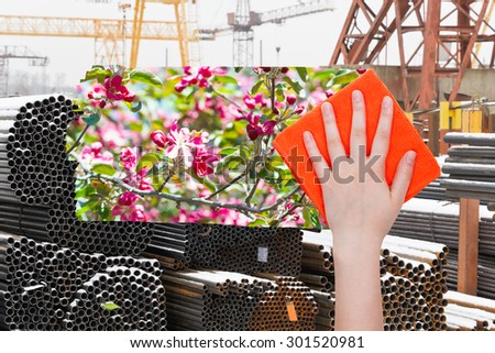 ecology concept - hand deletes industrial landscape by orange cloth from image and spring pink blossoms are appearing