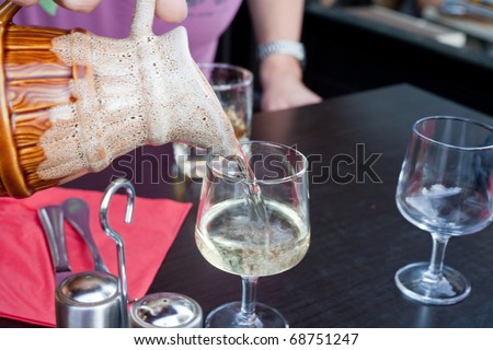 wine glass filled by white wine from jug