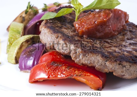 grilled meat with vegetables on a white plate close-up with shallow depth of field