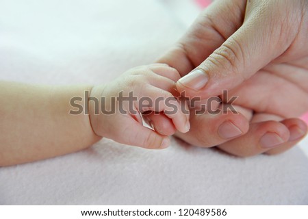 Baby\'s hand gripping adult finger