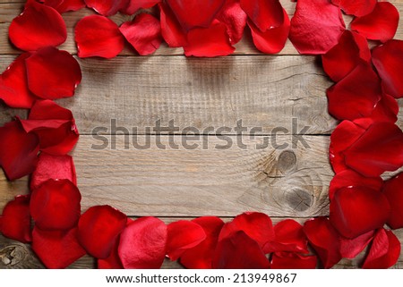 Frame of red rose petals on wooden background