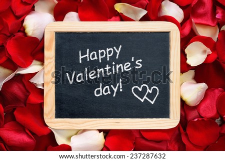 Happy Valentines day! text on blackboard on background of rose petals