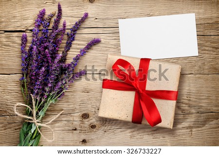 Flowers of salvia and gift box with visiting card on wooden background