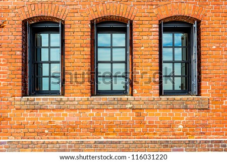 Black painted wood arched window in a red brick wall.