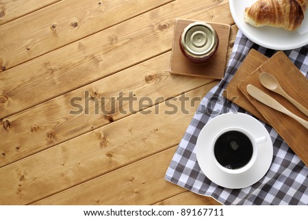 A cup of coffee with croissant on wooden table