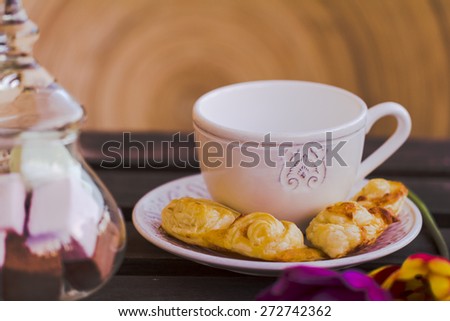 white coffee cup with pastries and sweets bonbonniere on wooden table with circular wooden background