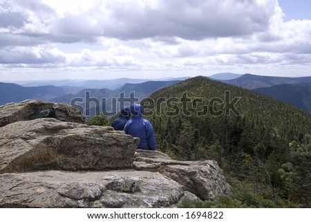 A couple of hikers take a rest at the top of mountain summit to enjoy the view and life