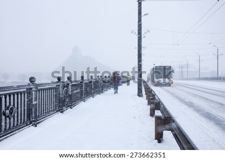 RIGA, LATVIA - DECEMBER 25, 2014: Unidentified Pedestrians and Bus with text RIGA on Stone bridge during heavy snow storm.