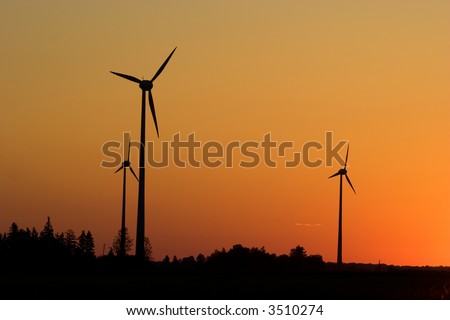 Three windturbines against dramatic sunset producing environment friendly energy