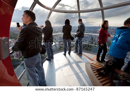 LONDON - JUNE 10: Unidentified tourists in London eye cabin observe the city from a bird's eye view on June 10, 2011 in London, UK. It's tallest Ferris wheel in Europe 135m (443ft) and most popular paid tourist attraction in UK