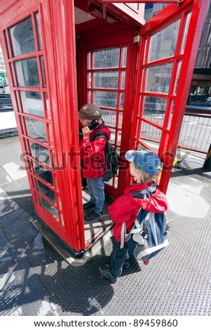 Boy talking in traditional red London pay phone box