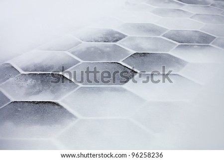 Hexagonal sidewalk tiles covered with snow and ice