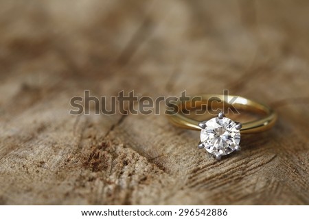 Solitaire engagement diamond ring won wooden organic background.