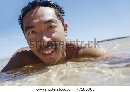 Asian guy half in the clean ocean water in Western Australia.