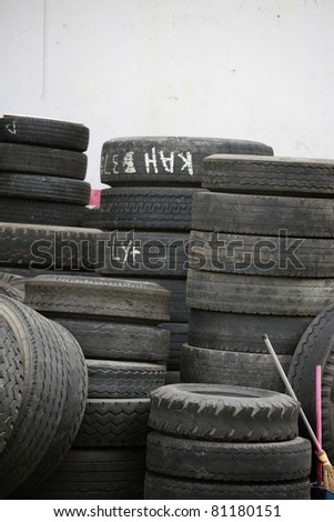 Piling up of used up truck tyres on white wall.