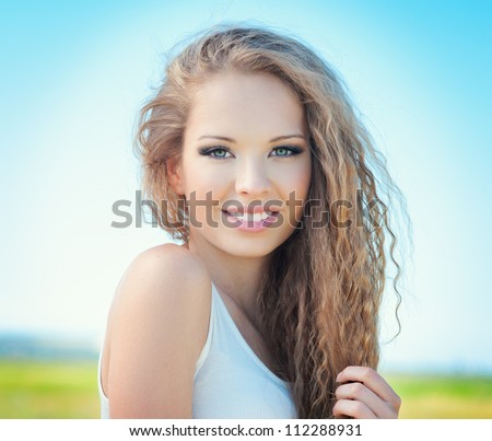 Beautiful smiling girl with long curly hair outdoor