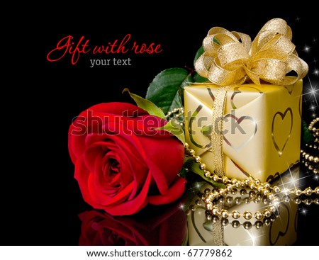 Gold gift with red rose on black background. Copy-space