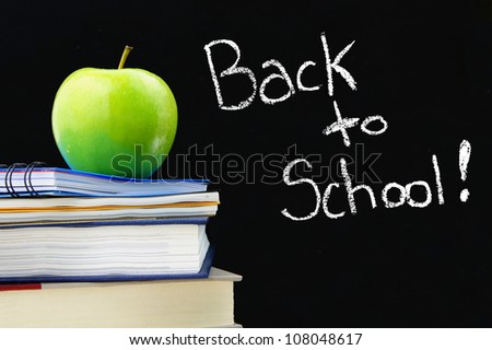 Back to School written on a blackboard with books and apple in front