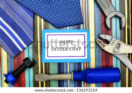 Happy Father Day tag with ties, and toy tools over patterned background