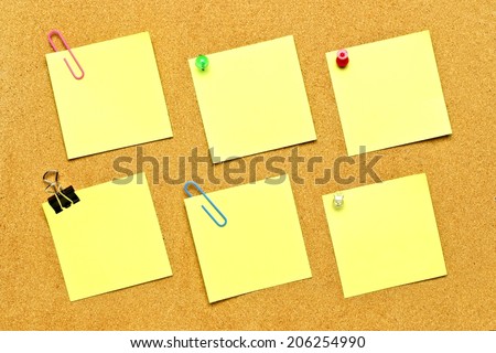 Blank sticky notes with various fasteners on bulletin board