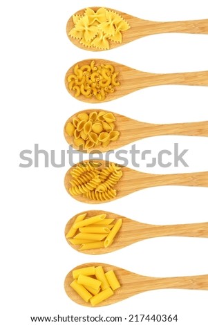 Vertical arrangement of spoons filled with various dry pasta over white