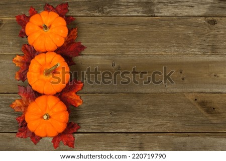 Autumn leaves and pumpkin border against aged wood