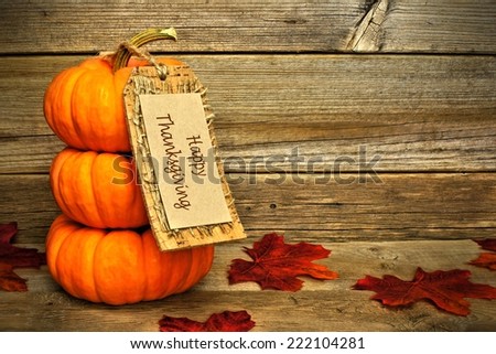 Stack of mini pumpkins with Happy Thanksgiving tag on a wooden background