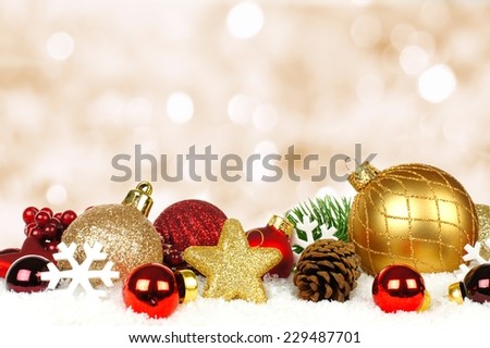 Gold and red Christmas ornament border in snow with twinkling gold light background