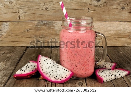 Pink raspberry, dragon fruit smoothie with fruit slices on an old wood background