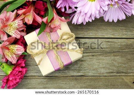 Rustic gift box with corner border of flowers on wood background