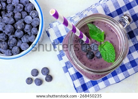 Blueberry smoothie with mint in mason jar mug, downward view on white marble