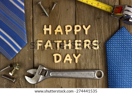Happy Fathers Day wooden letters on a rustic wood background with tools and ties frame